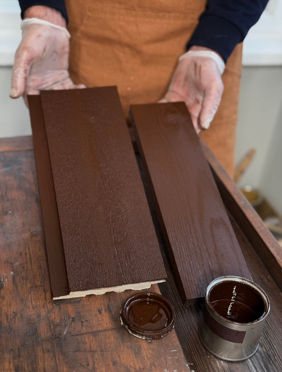 A person holding wooden boards painted with Paint Eco natural linseed oil paint in Elk shade, with an open can beside them.