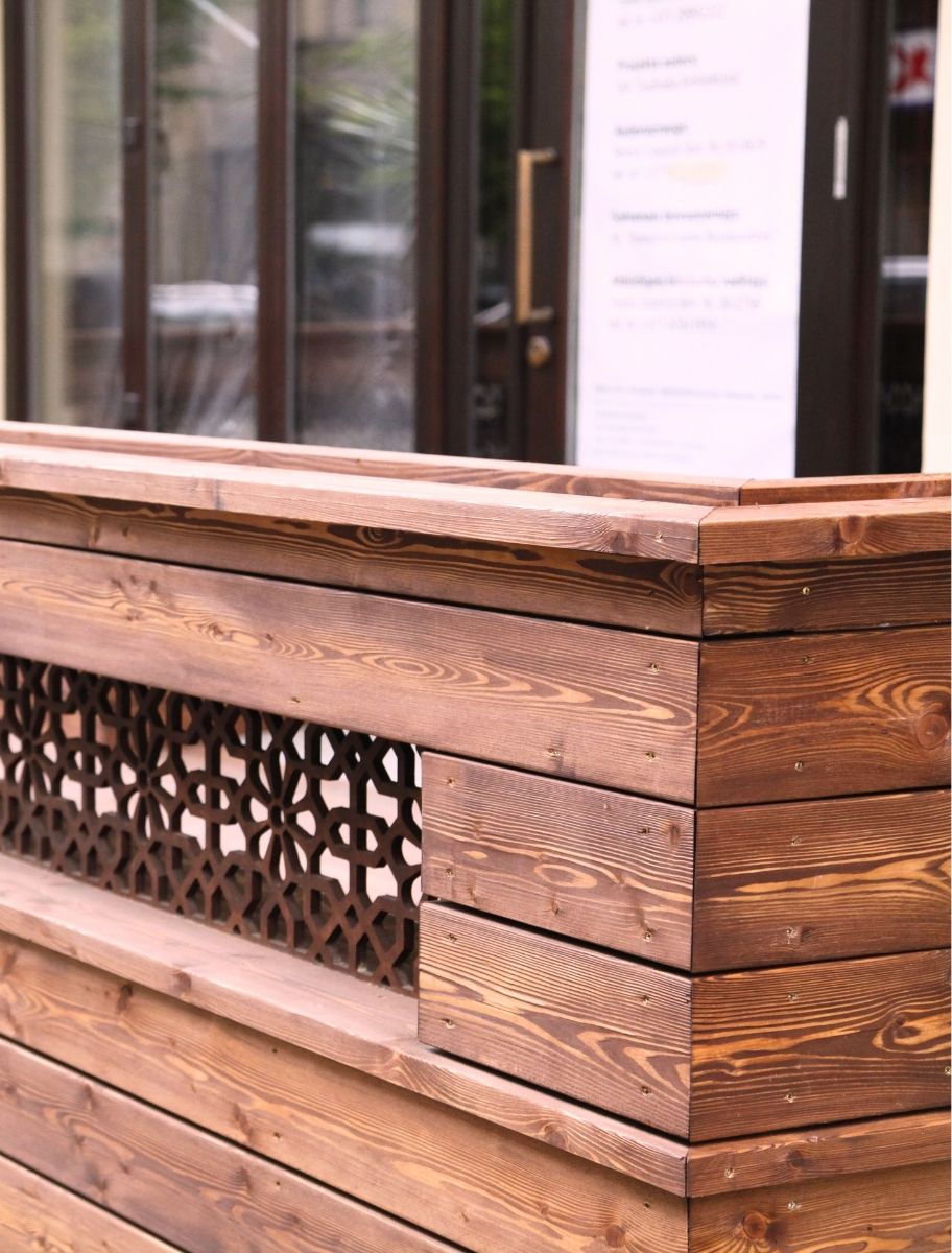 Outdoor wooden terrace partition treated with PAINT ECO's natural stain, highlighting a rich wood tone and enhanced grain with a decorative panel insert.