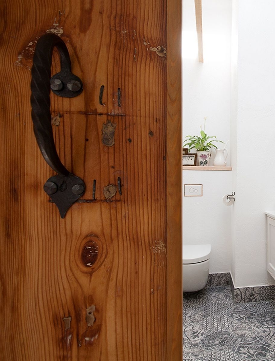 Linseed oil-finished wooden door with wrought iron handle, opening to a bathroom.