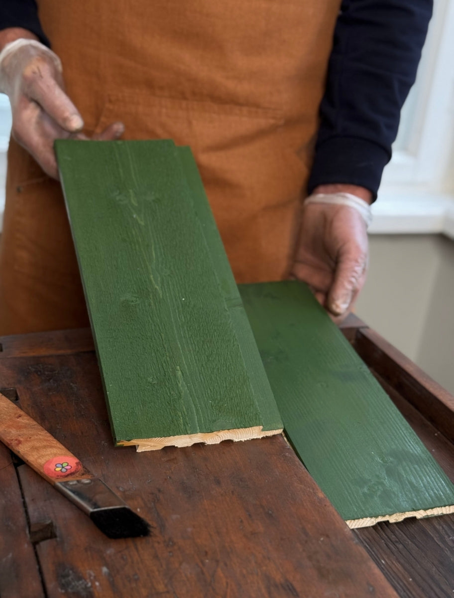 A person holding wooden boards painted with Paint Eco natural linseed oil paint in Needle shade.