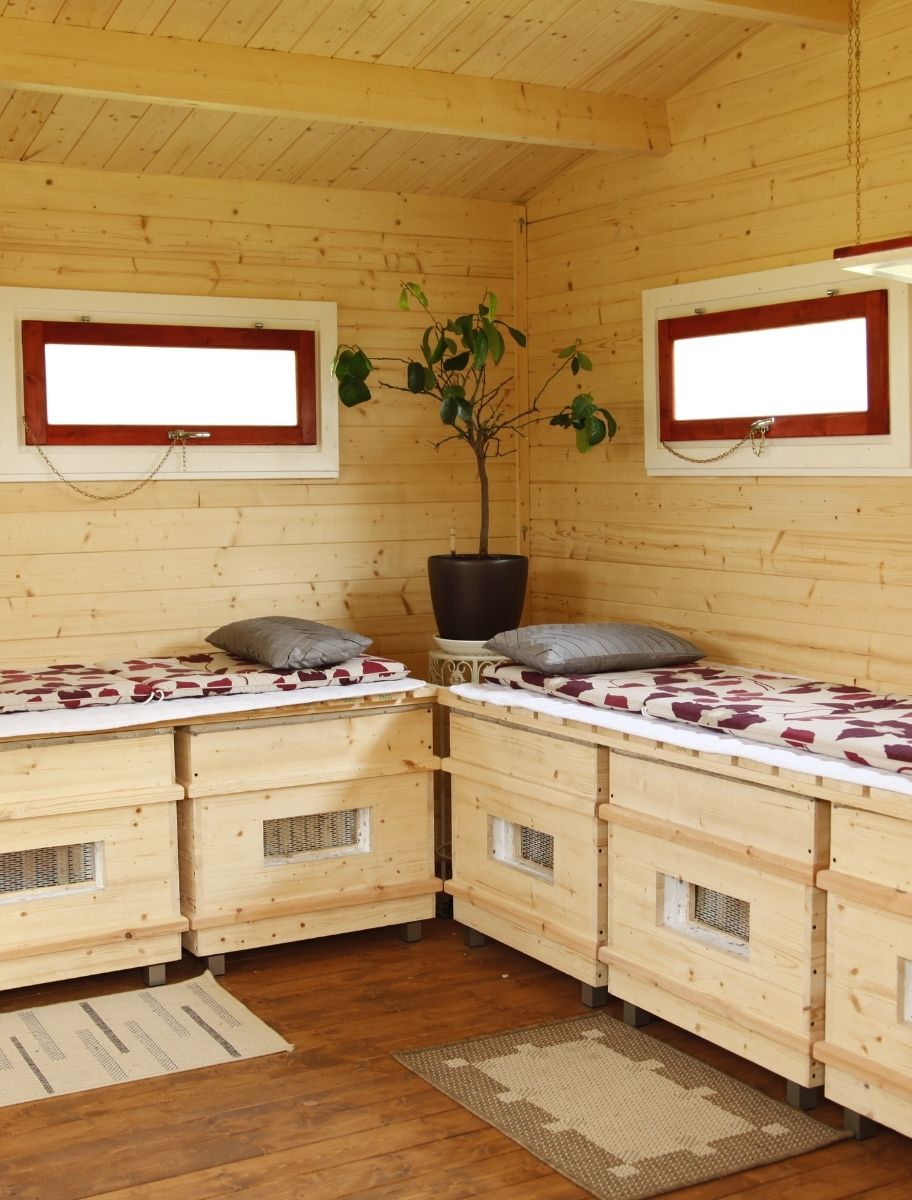 A cozy wooden interior with built-in wooden seating, illuminated by natural light, showcasing treated wood surfaces.