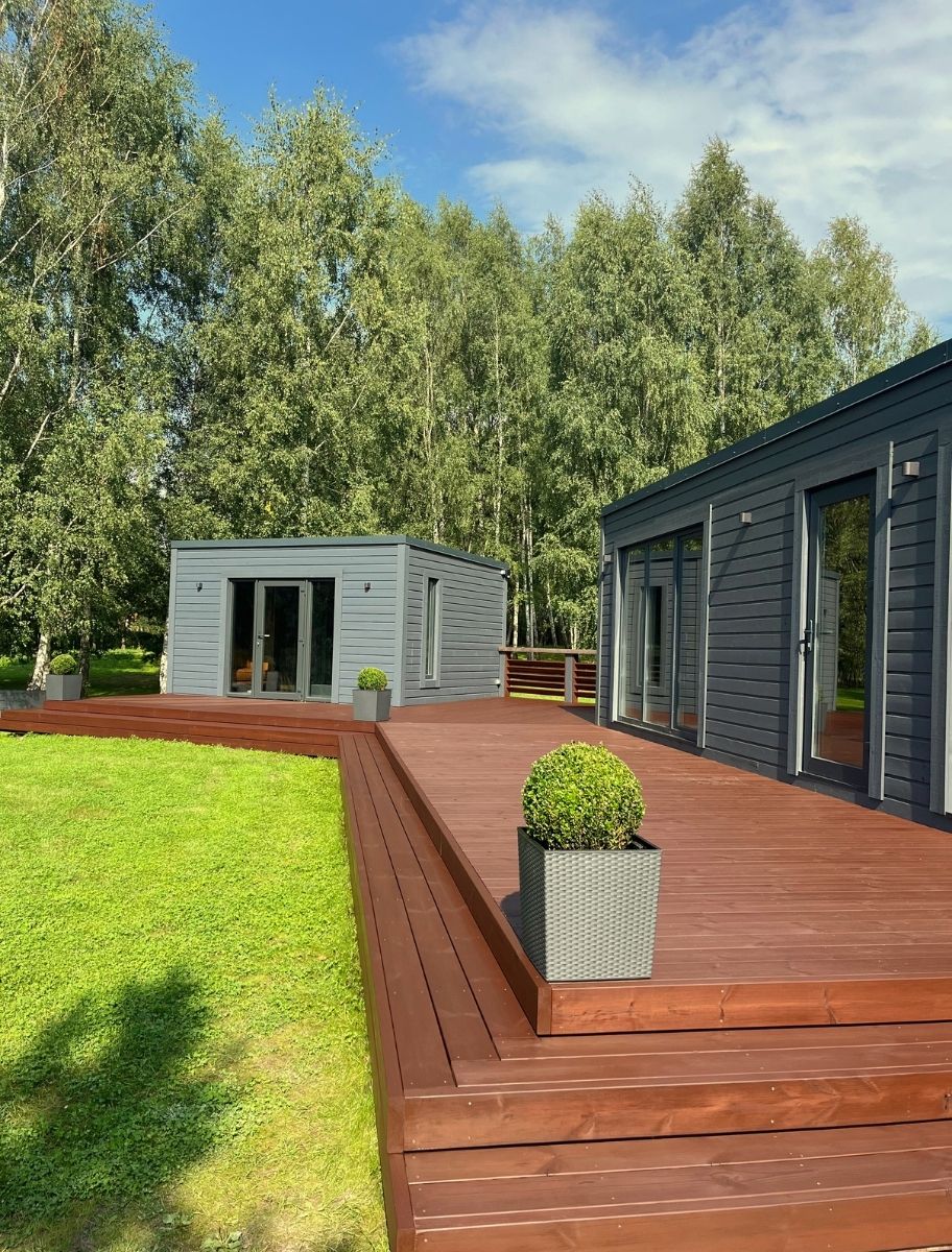 Modern wooden terrace stained with PAINT ECO's natural wood stain, enhancing durability and rich color. Surrounded by greenery and contemporary buildings for a stylish outdoor space.