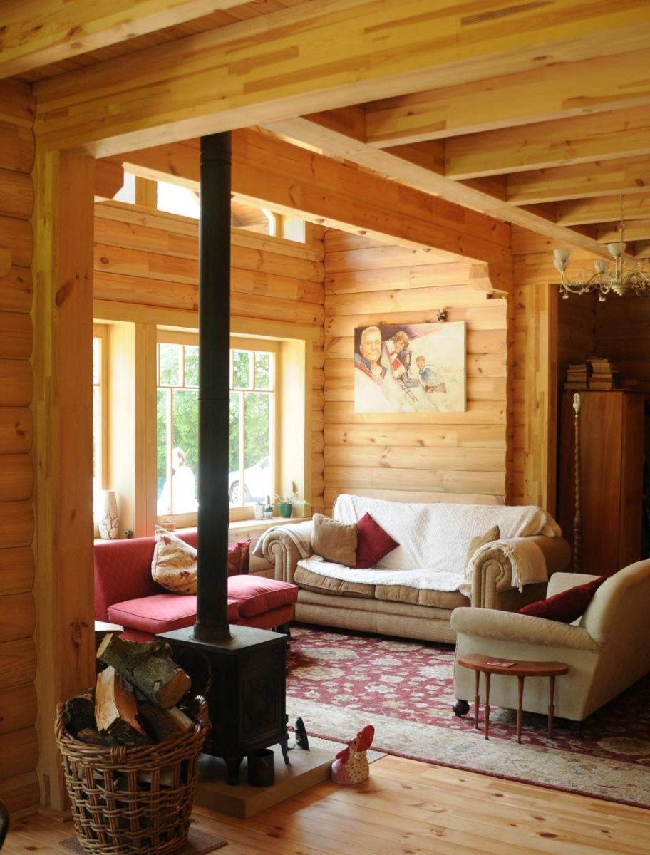 Cozy log cabin interior with wooden walls treated with linseed oil, featuring a fireplace and rustic decor.