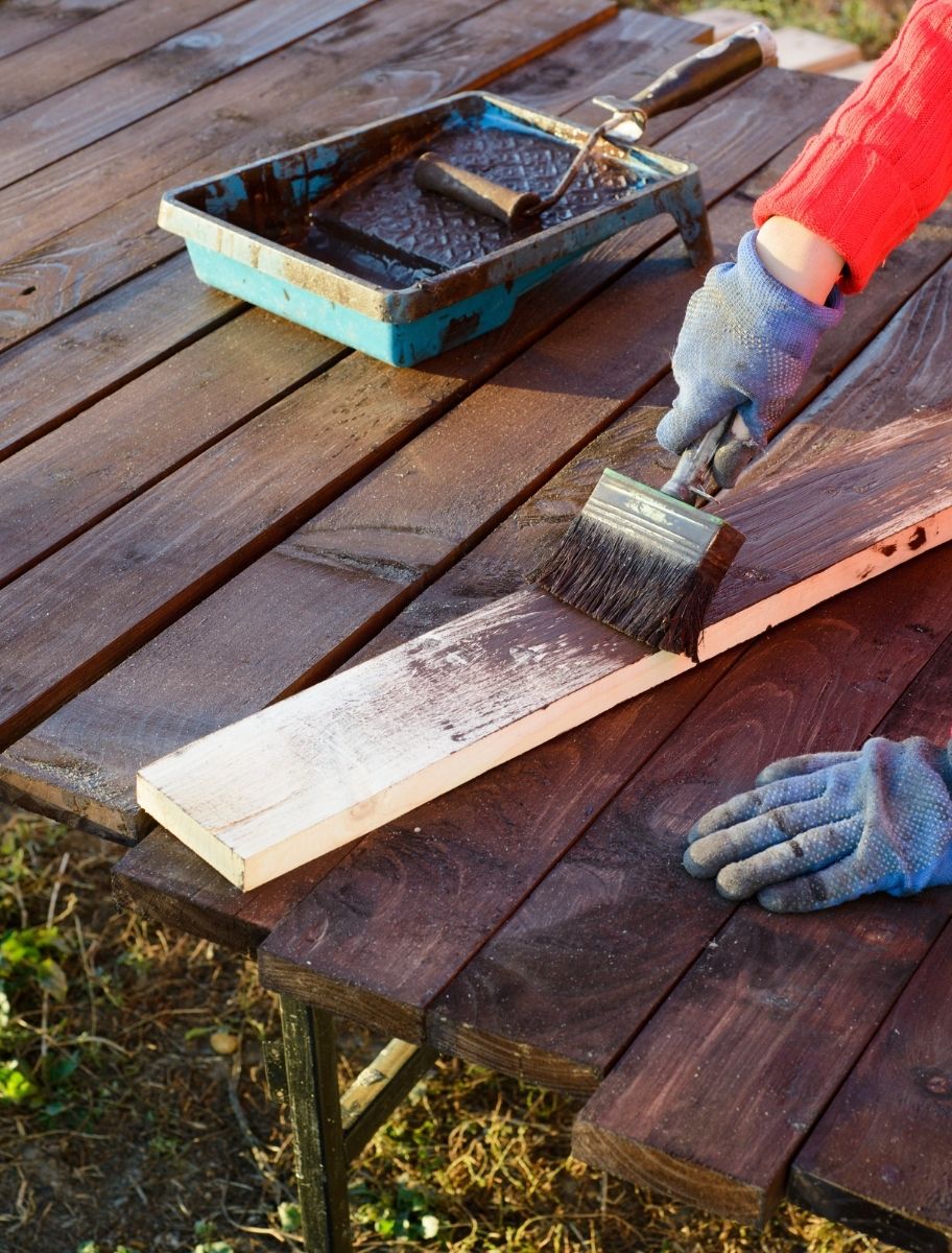 Applying PAINT ECO Tar Oil to wooden decking for weather resistance and long-lasting protection.