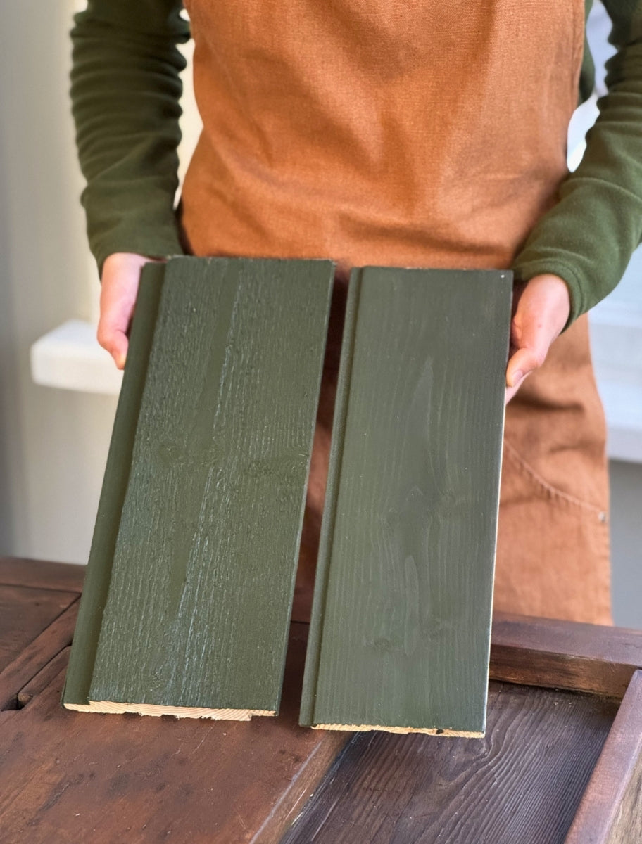 A person holding wooden boards painted with Paint Eco natural linseed oil paint in Forest green shade.