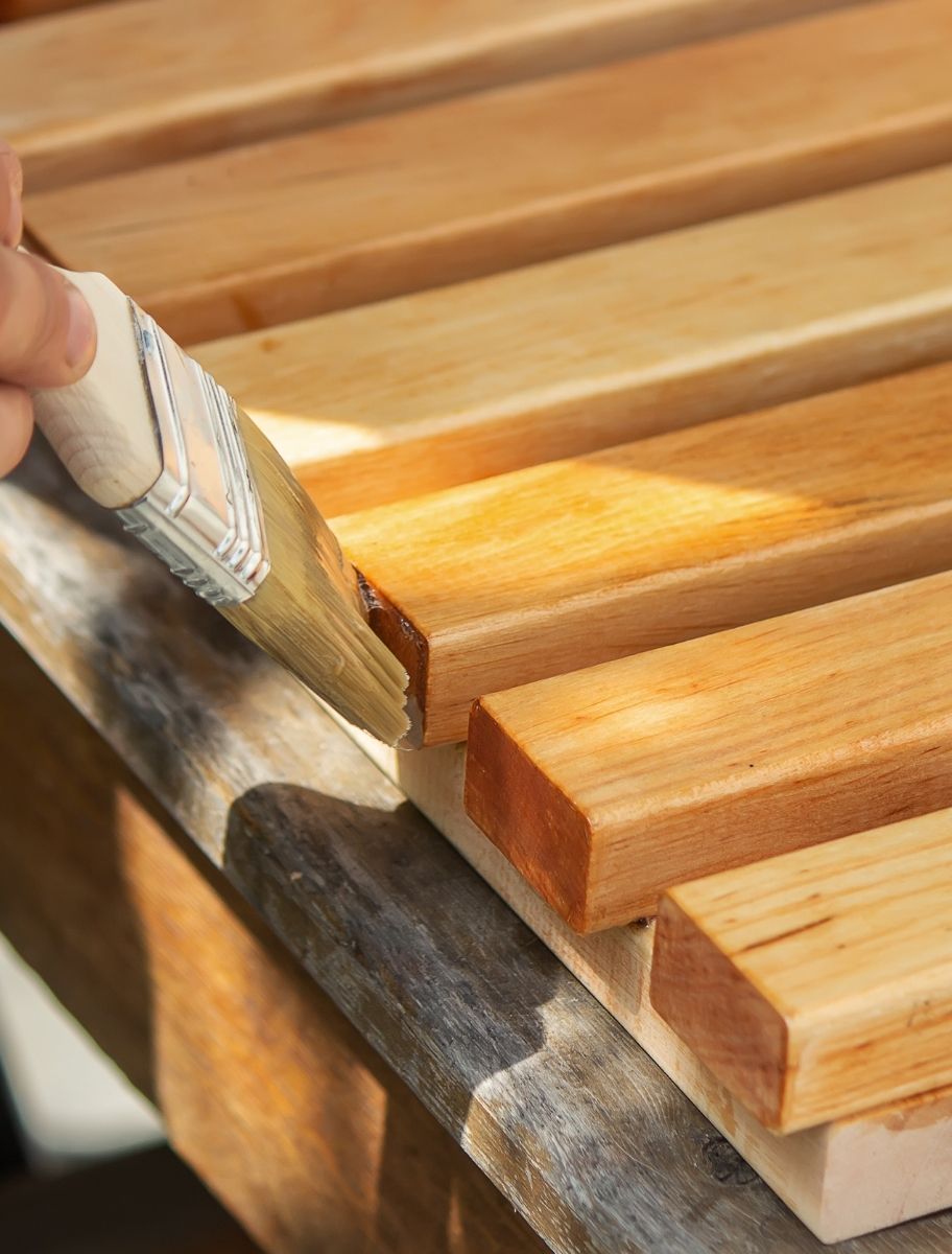 Applying linseed oil with a brush on wooden slats for natural wood protection and enhancement.